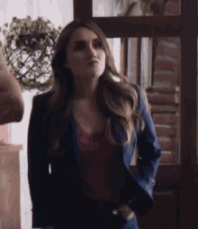 a woman is wearing a blue jacket and a purple top .