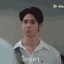 a young man in a white shirt is making a funny face in front of a we logo .