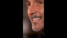 a close up of a man 's face with a beard and a smile on his face .