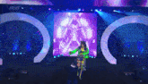 a woman in a green and yellow outfit is on a stage with a aew logo in the background