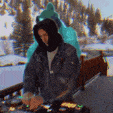 a man in a hooded jacket is playing a dj set