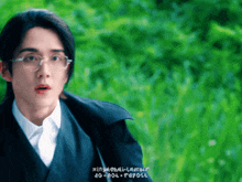 a man wearing glasses and a black jacket stands in front of a green background