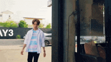 a young man in a white shirt and a blue shirt is standing in front of a building .