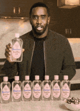 a man holds up a row of bottles of bad boy oil