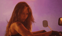a woman is sitting on a motorcycle with a purple background