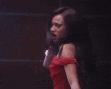 a woman in a red off the shoulder dress is making a face