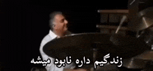 a man is playing drums in a dark room with a foreign language .