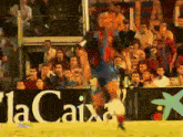 a soccer game is being played in front of a lacaixa sign