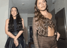 two women are standing next to each other in a hallway
