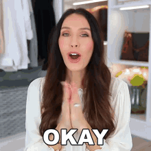 a woman in a white shirt says okay in front of a closet