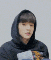 a young man wearing a black hoodie is making a face .