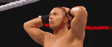 a shirtless wrestler with his hands behind his head .