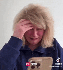 a woman is crying while looking at a cell phone with the words oh god written on it