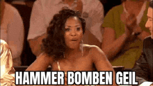 a woman is sitting in a crowd of people and saying `` hammer bomben gail `` .