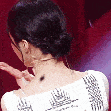 a woman wearing a white top with a tattoo on her back that says aesthetic