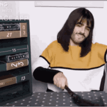 a man with long hair is sitting at a table with a brush