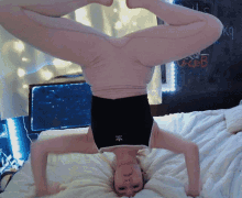 a woman is doing a handstand on a bed with a chalkboard behind her that says " goals "