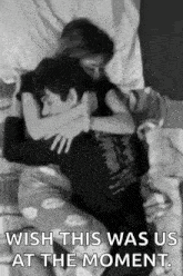 a black and white photo of a man and a woman hugging each other on a bed .