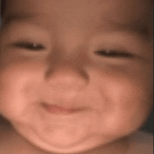 a close up of a baby 's face with his eyes closed smiling .