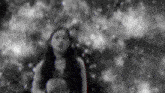 a black and white photo of a woman standing in the woods .