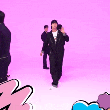 a man in a black jumpsuit is walking on a purple background