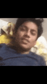 a man in a blue shirt is laying on a bed with his eyes closed
