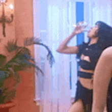 a woman is drinking water from a bottle while standing in a room .