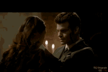 a man and a woman are looking at each other with the words the originals 02 on the bottom right