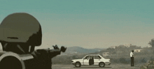 a soldier is pointing a gun at a car that is parked on the side of the road