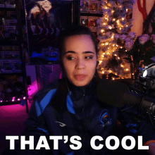 a woman sitting in front of a christmas tree with the words that 's cool on the bottom