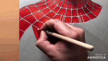 a hand is holding a pencil and drawing a spider man