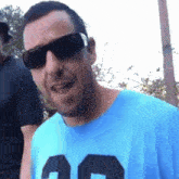 a man wearing sunglasses and a blue t-shirt with the number 20 on it