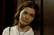 a woman leaning against a wall wearing a choker necklace
