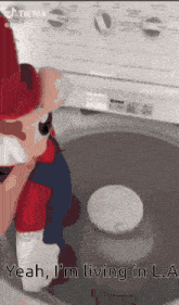 a stuffed mario is sitting in a washing machine with the caption yeah i 'm living in la