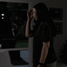 a woman in a black shirt is sitting on a couch in a dark room
