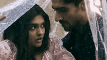 a man and a woman are looking at each other under an umbrella .