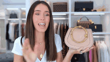 a woman in a white shirt is holding a pink purse with a gold handle