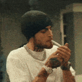 a man wearing a black beanie is smoking a cigarette