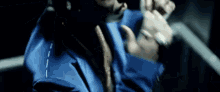 a man wearing a blue jacket and a gold tie is holding a microphone