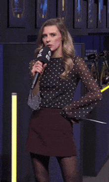a woman in a polka dot top is holding a microphone with the word extreme on it