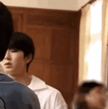a group of people are standing in a room looking at something .