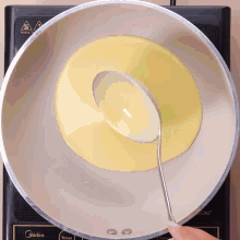 a person is pouring liquid into a pan that says midea on the bottom