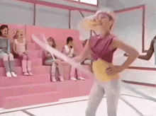 a woman in a pink top and white pants is dancing in front of a crowd