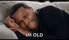 a man is laying on a couch with his eyes closed and crying while saying `` im old '' .