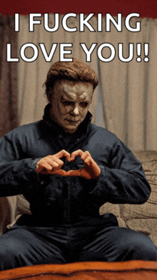 a man in a mask is making a heart shape with his hands and says i fucking love you !