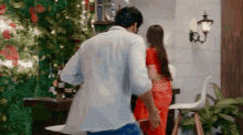 a man in a white shirt is standing next to a woman in a red dress