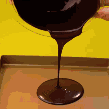 chocolate is poured into a pan on a yellow background