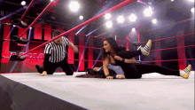 a referee watches two women wrestle in a wrestling ring with the word team in the background