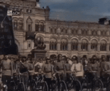 a group of people riding bicycles in front of a building that says 24ack