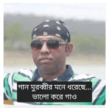 a man wearing sunglasses and a bandana is standing in front of a river .